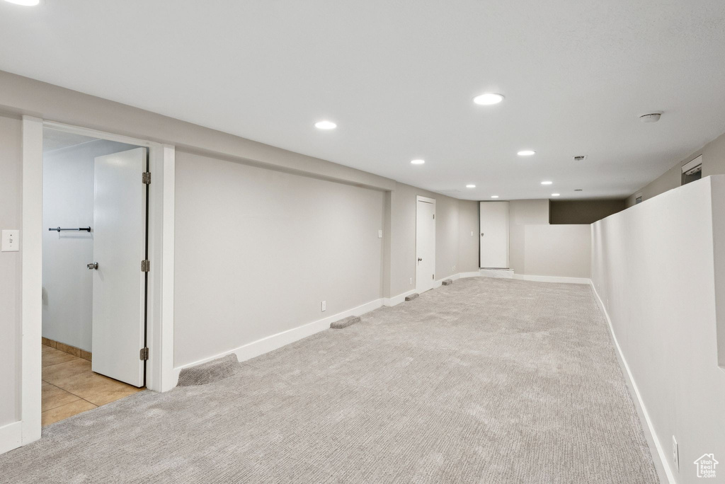 Finished below grade area featuring light colored carpet and recessed lighting