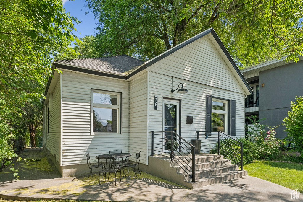 Shotgun-style home with a patio area and roof with shingles