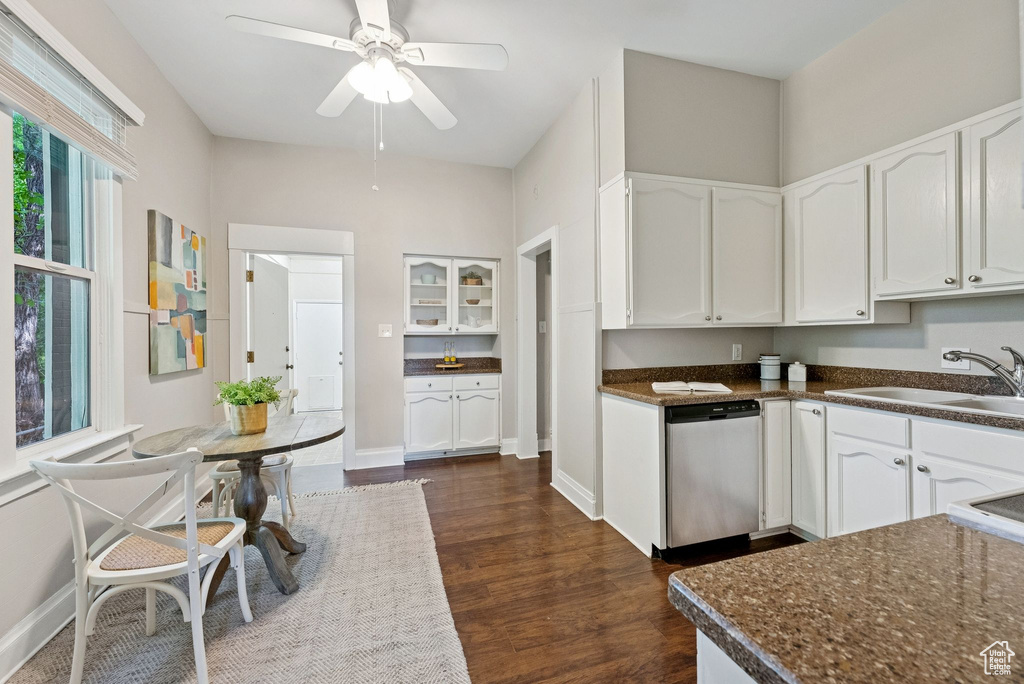 Kitchen featuring stainless steel dishwasher, white cabinets, dark wood finished floors, a ceiling fan, and glass insert cabinets