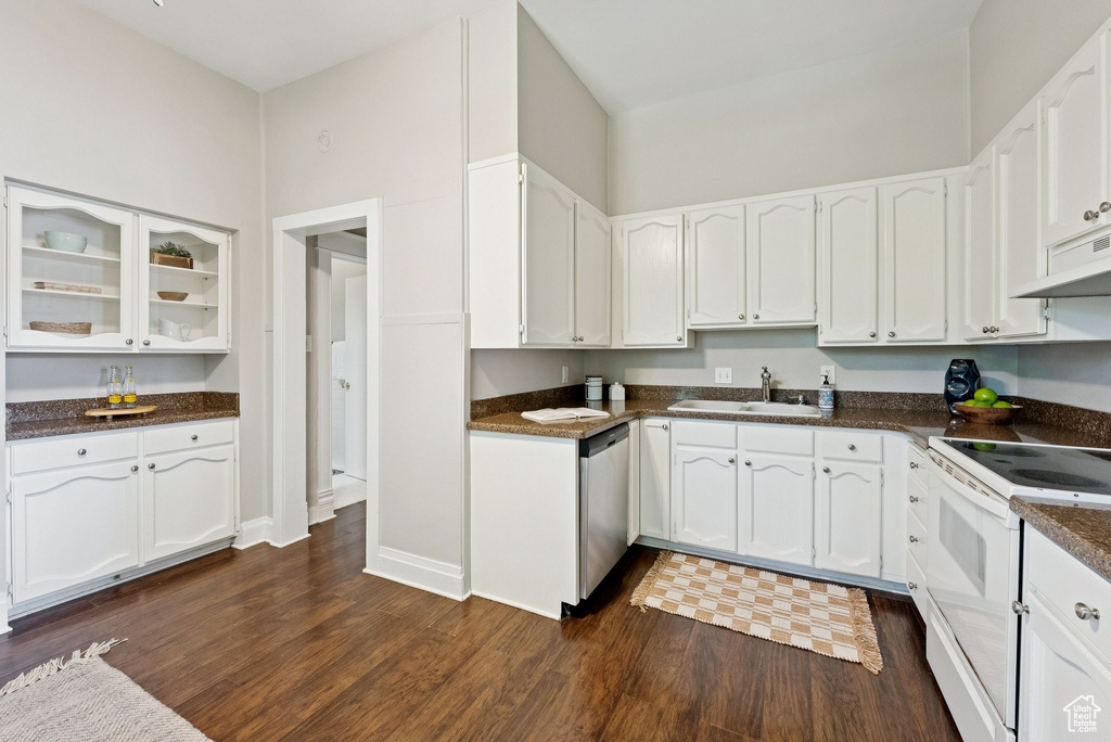 Kitchen featuring white range with electric cooktop, stainless steel dishwasher, dark countertops, white cabinets, and dark wood finished floors