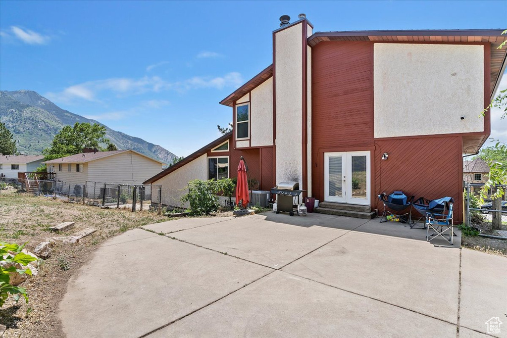 Rear view of house featuring french doors, a patio area, a mountain view, stucco siding, and a chimney
