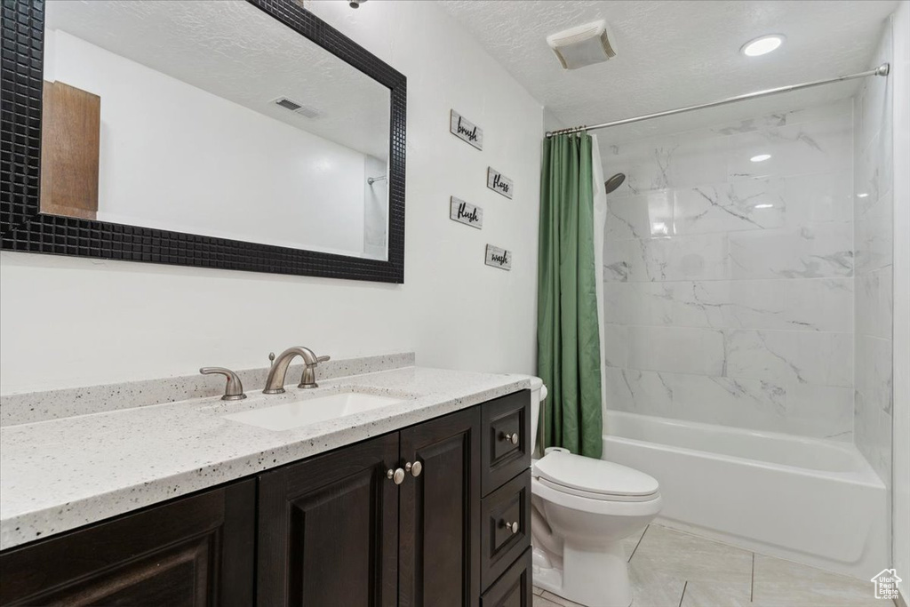 Bathroom featuring shower / bathtub combination with curtain, vanity, tile patterned floors, and a textured ceiling