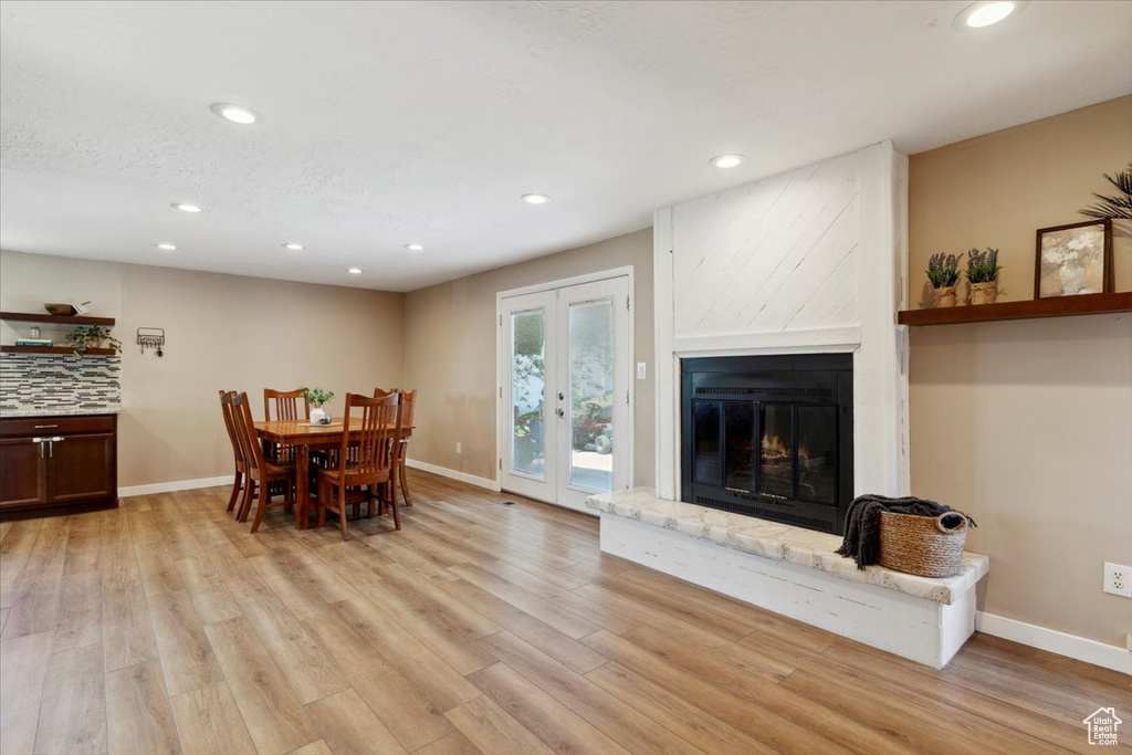 Dining area with recessed lighting, light wood-style floors, a large fireplace, and french doors
