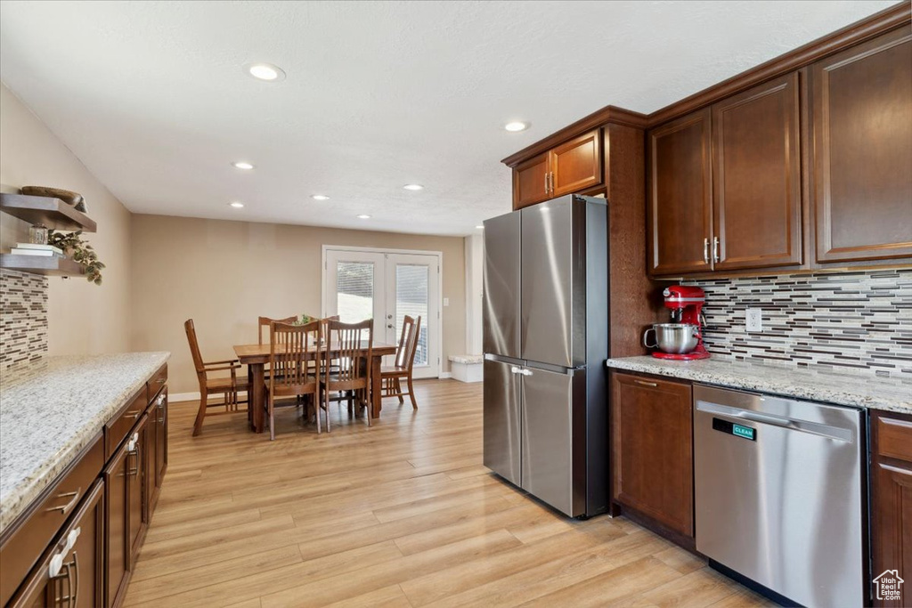 Kitchen featuring stainless steel appliances, light wood finished floors, recessed lighting, tasteful backsplash, and light stone countertops