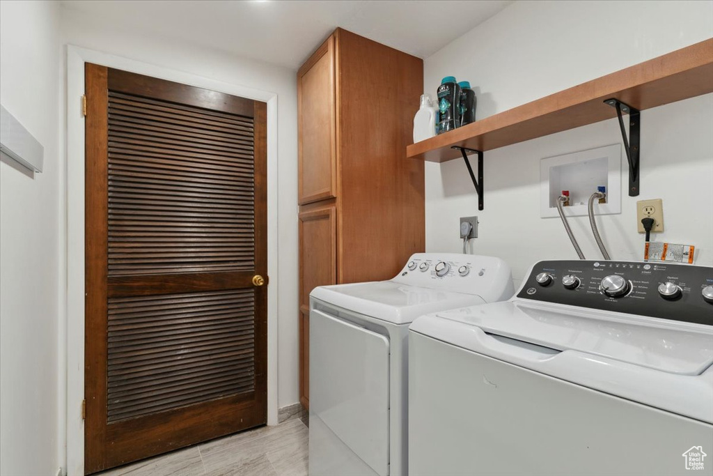 Laundry room with cabinet space, washing machine and dryer, and light wood-style flooring