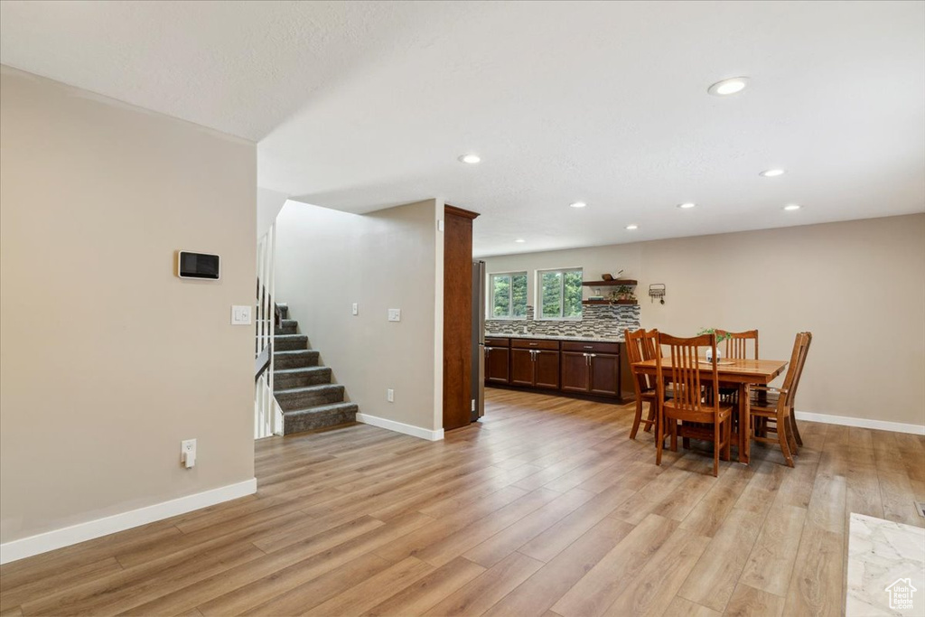 Dining area with light wood-style floors, recessed lighting, and stairs