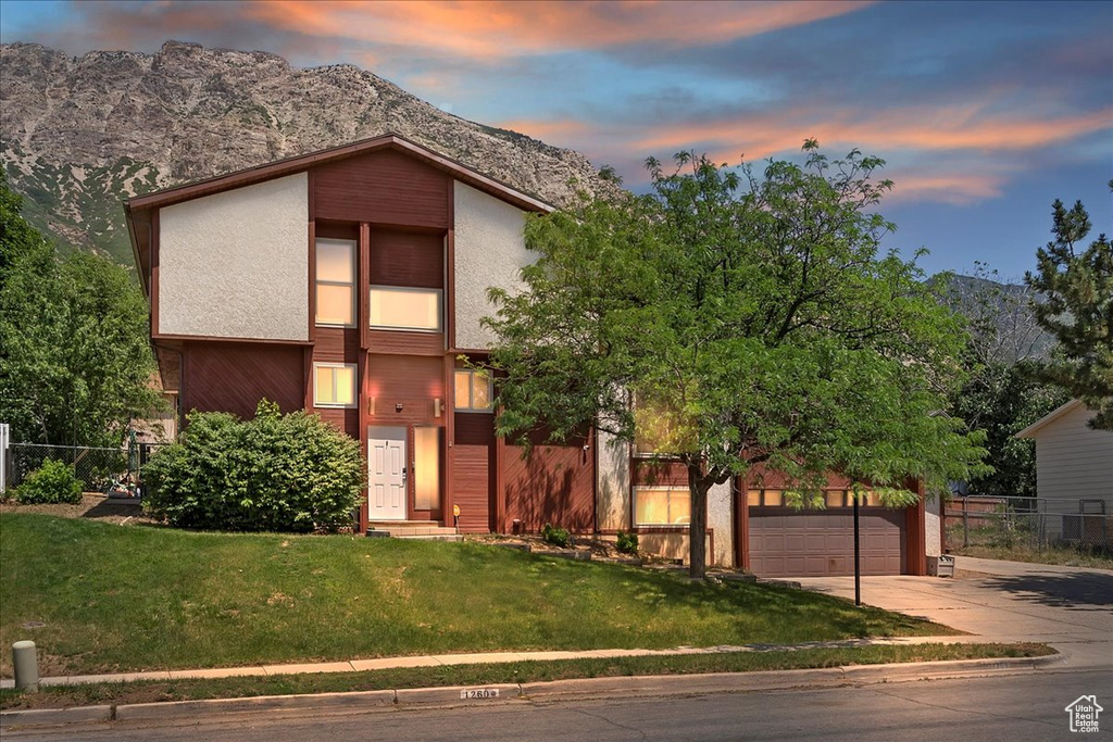 Mid-century home with concrete driveway, a garage, a mountain view, and stucco siding
