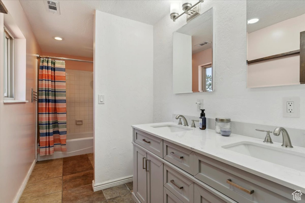 Bathroom featuring double vanity, shower / bath combo with shower curtain, and tile patterned floors