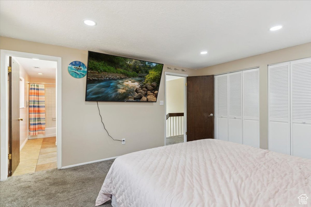 Bedroom featuring light carpet, two closets, recessed lighting, and ensuite bathroom