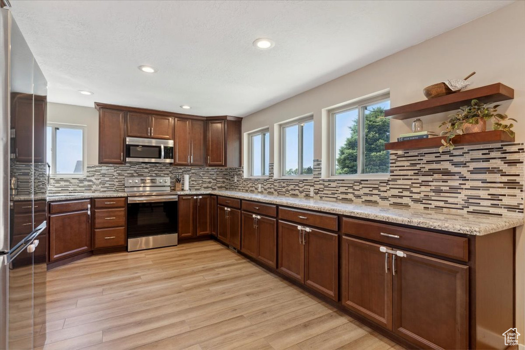 Kitchen with appliances with stainless steel finishes, light wood-style floors, decorative backsplash, and recessed lighting