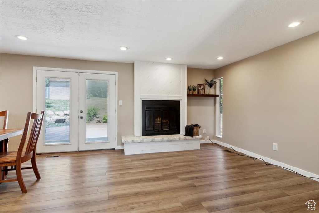 Unfurnished living room with french doors, wood finished floors, recessed lighting, a fireplace, and a textured ceiling