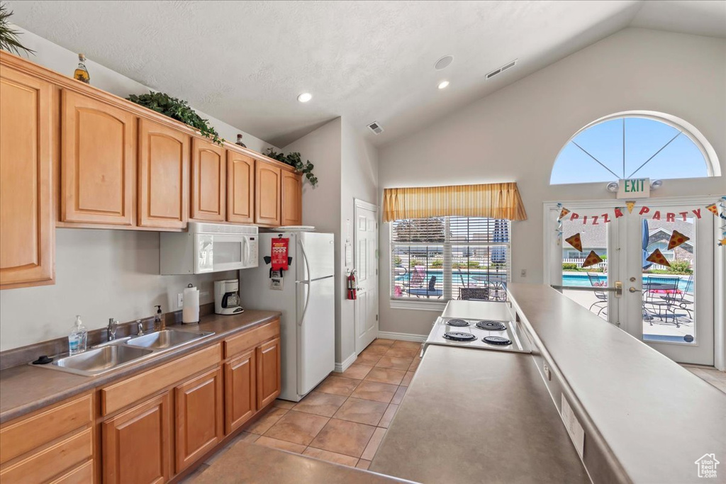 Kitchen with white appliances, recessed lighting, french doors, light tile patterned flooring, and high vaulted ceiling
