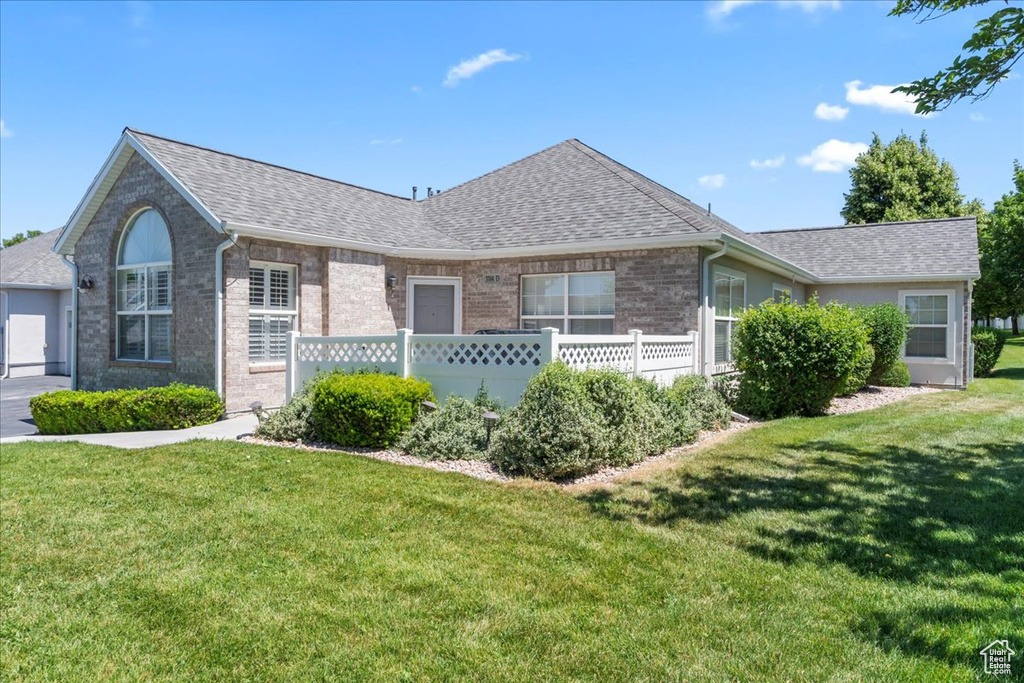 Single story home with a front yard, a shingled roof, and brick siding