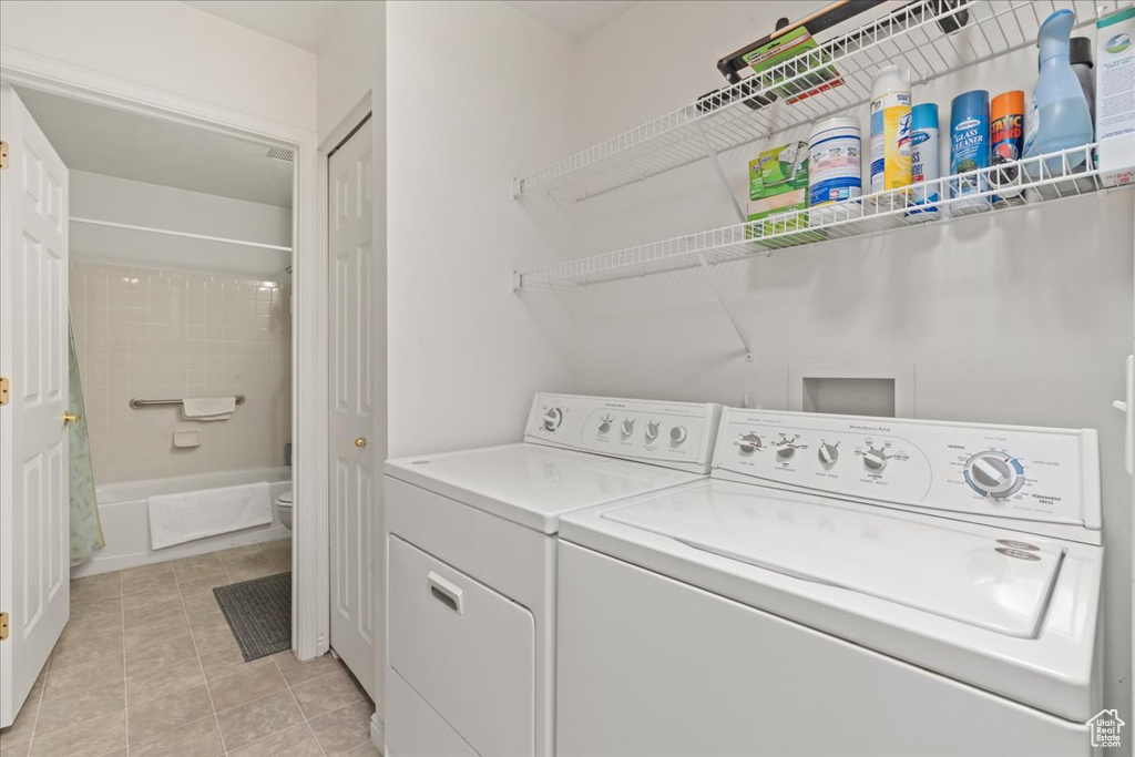 Laundry room with washing machine and clothes dryer and light tile patterned floors