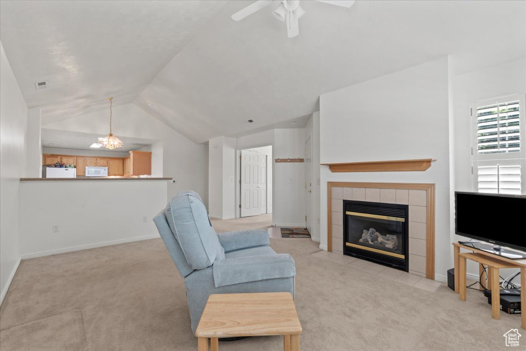 Living area with carpet floors, vaulted ceiling, a tiled fireplace, and ceiling fan