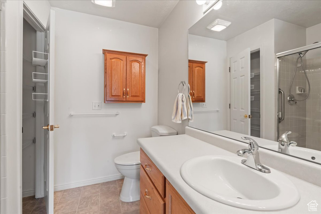 Bathroom featuring vanity, a tile shower, and tile patterned flooring