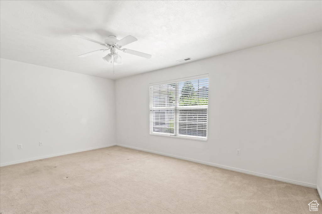 Spare room featuring light carpet and a ceiling fan