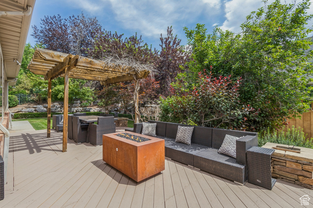 Wooden terrace with an outdoor living space with a fire pit and a pergola
