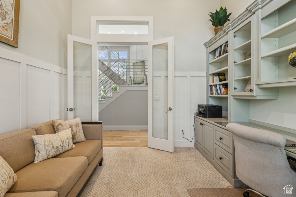 Office area with a decorative wall, french doors, wainscoting, built in study area, and light carpet