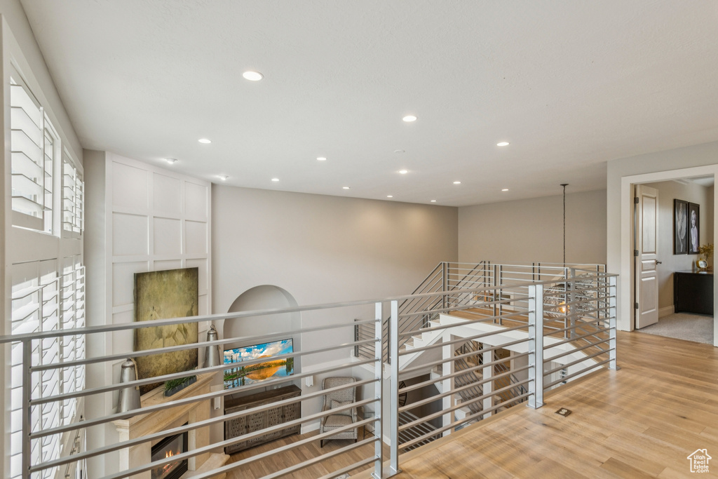 Corridor with an upstairs landing, recessed lighting, and wood finished floors