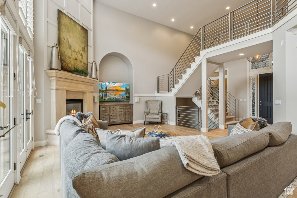 Living room with stairway, a high ceiling, a glass covered fireplace, recessed lighting, and french doors