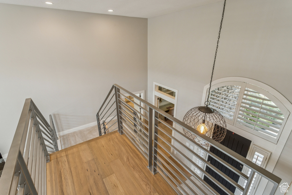 Stairway with wood finished floors, recessed lighting, and a high ceiling