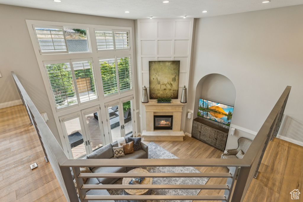 Living room with a high ceiling, a fireplace, recessed lighting, and wood finished floors