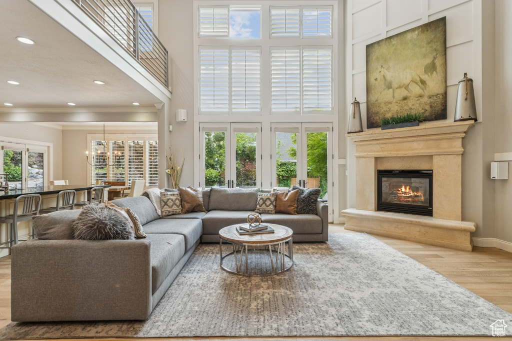Living room with wood finished floors, a high ceiling, recessed lighting, a glass covered fireplace, and a chandelier