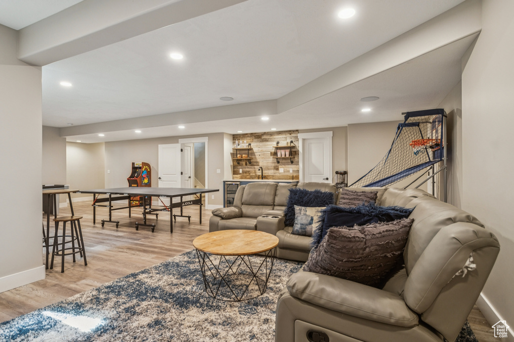 Living area featuring bar with sink, light wood finished floors, and recessed lighting