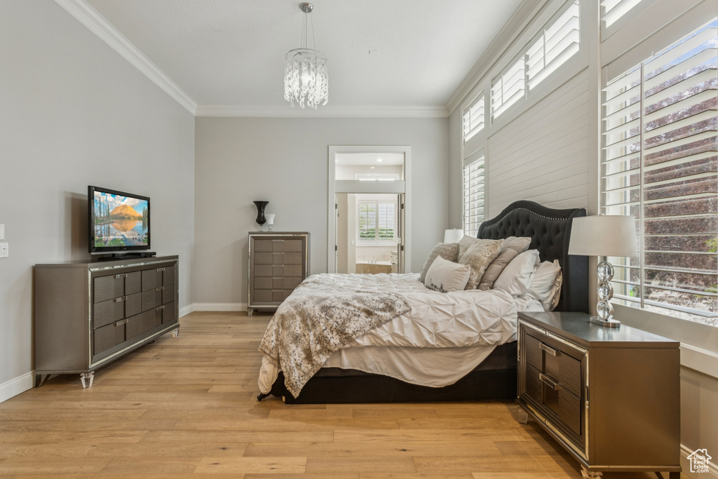 Bedroom with ornamental molding, light wood finished floors, a chandelier, and ensuite bath