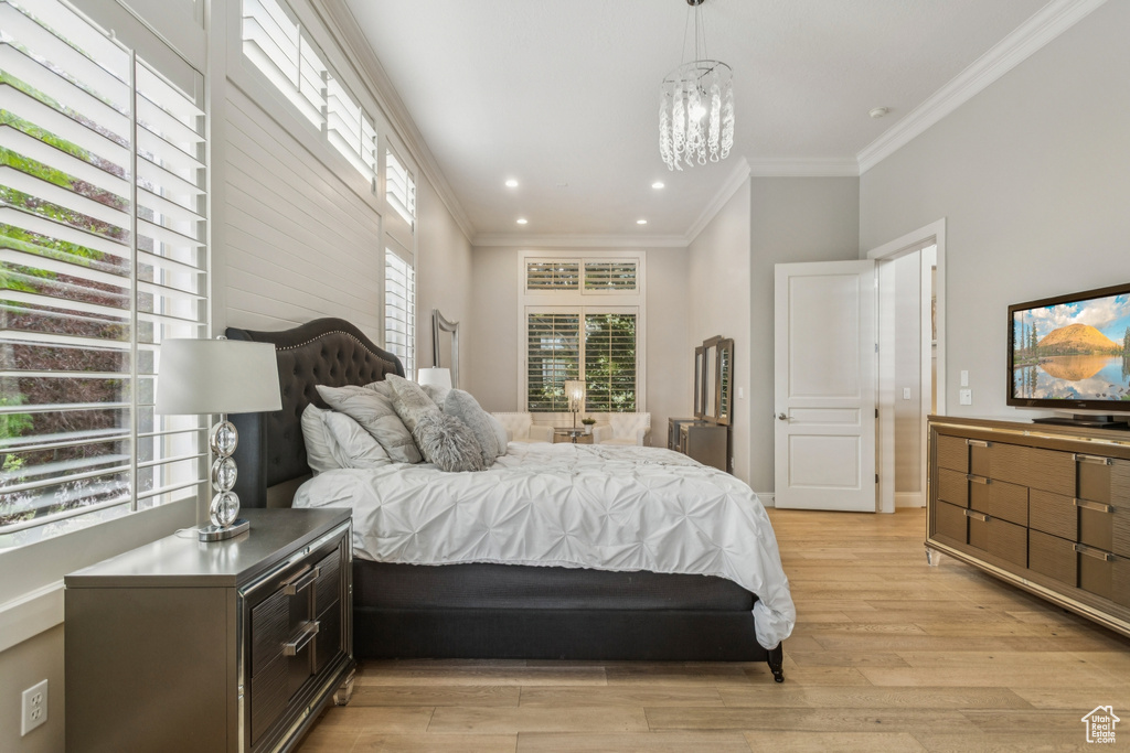 Bedroom featuring light wood-type flooring, recessed lighting, crown molding, and a chandelier