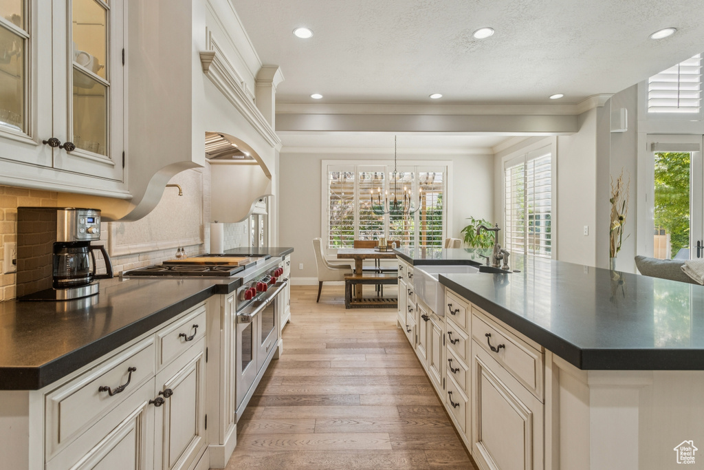 Kitchen featuring double oven range, dark countertops, light wood-style flooring, recessed lighting, and decorative backsplash