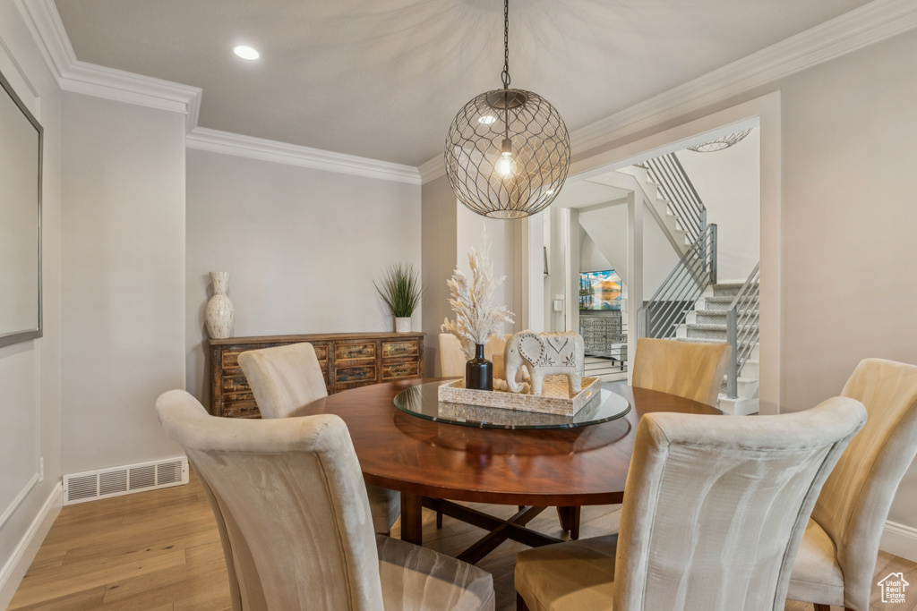 Dining space featuring light wood-type flooring, stairs, crown molding, and recessed lighting