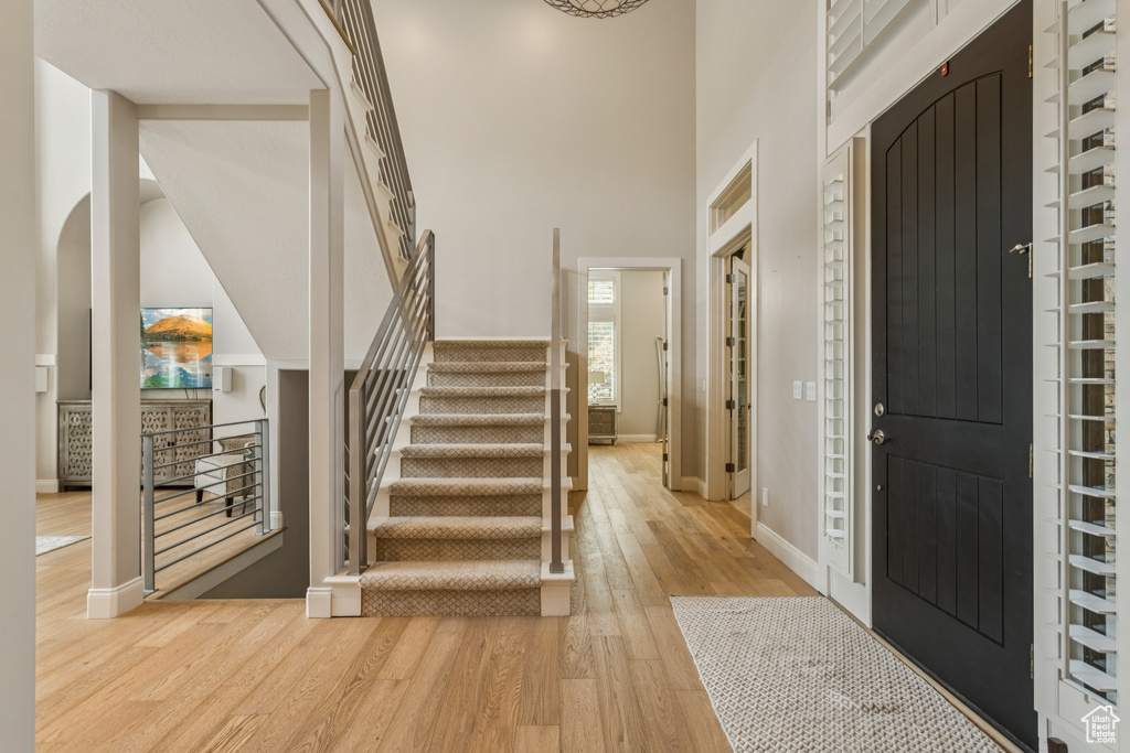 Foyer featuring light wood-style floors, stairs, and a high ceiling