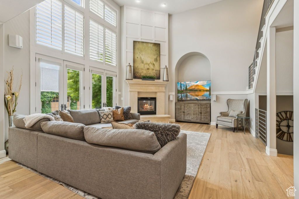 Living room with a high ceiling, a fireplace, plenty of natural light, and light wood-style flooring