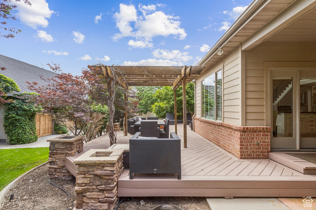 Deck featuring a pergola, outdoor dining area, and an outdoor living space with a fire pit