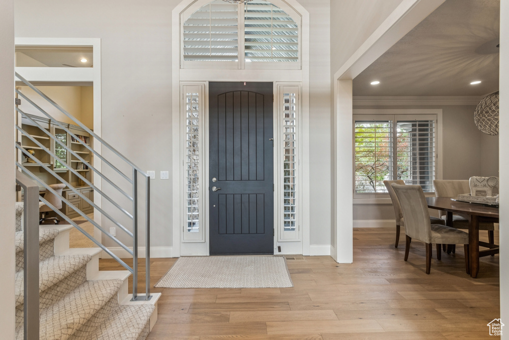 Foyer entrance featuring wood finished floors, stairs, crown molding, and recessed lighting