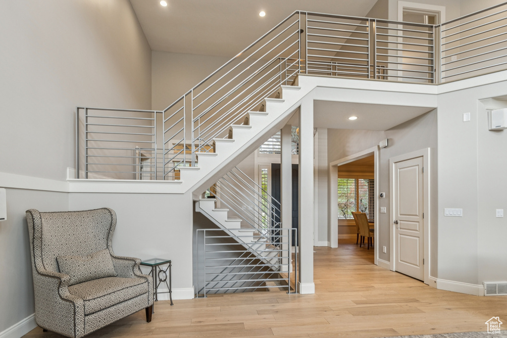 Staircase featuring a high ceiling, wood finished floors, and recessed lighting