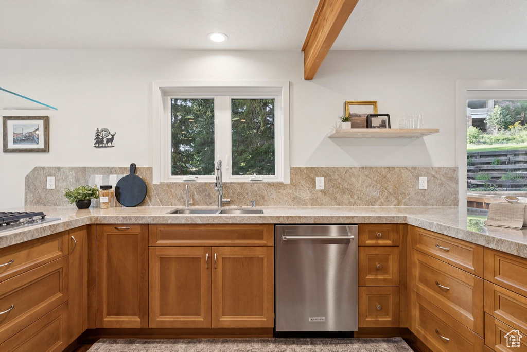 Kitchen featuring stainless steel appliances, beam ceiling, brown cabinetry, tasteful backsplash, and light countertops