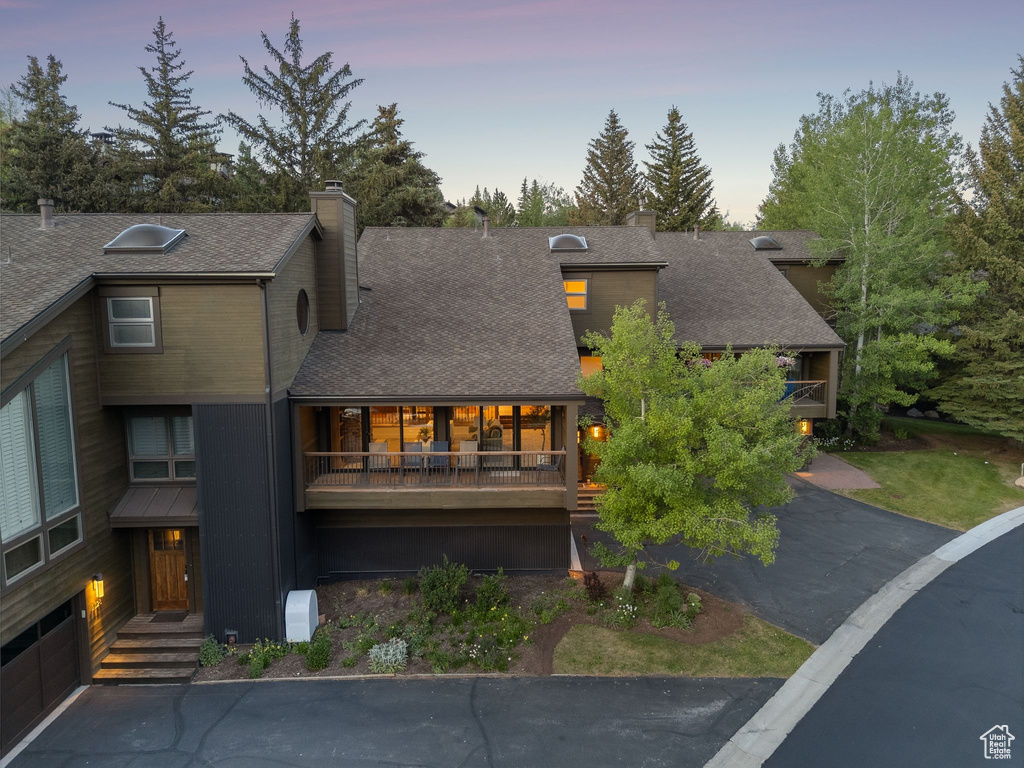 Back of house with a chimney and a shingled roof