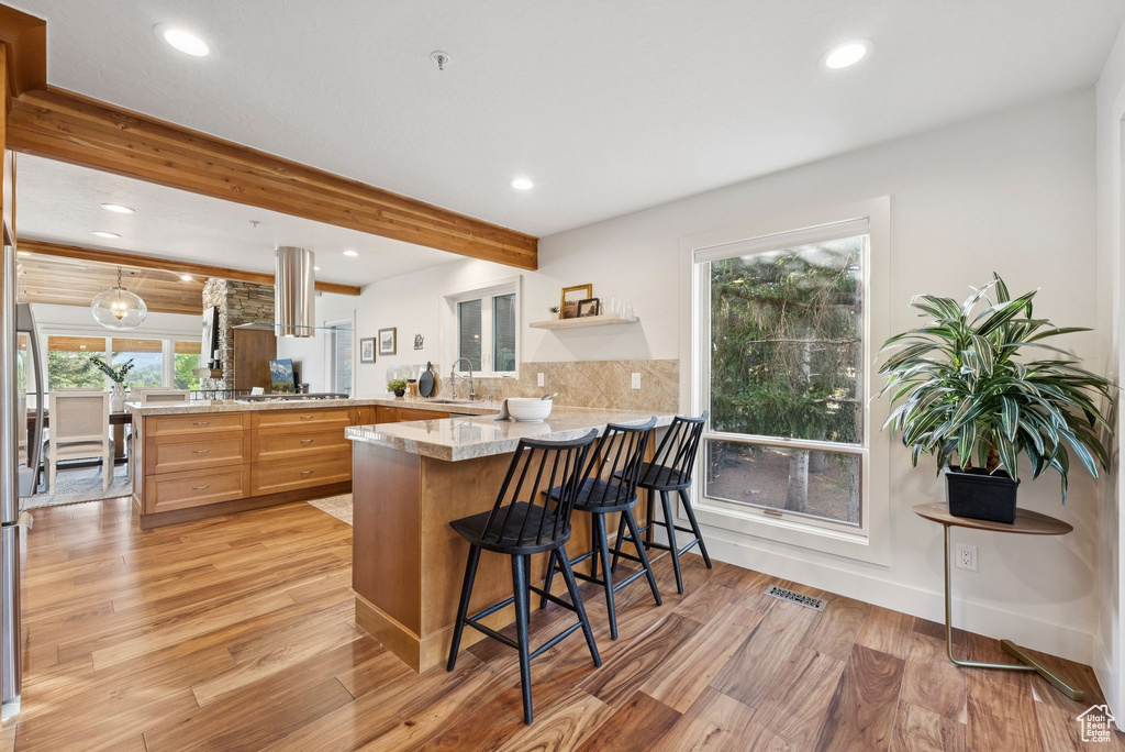 Kitchen with a peninsula, light wood-style flooring, recessed lighting, beamed ceiling, and decorative backsplash