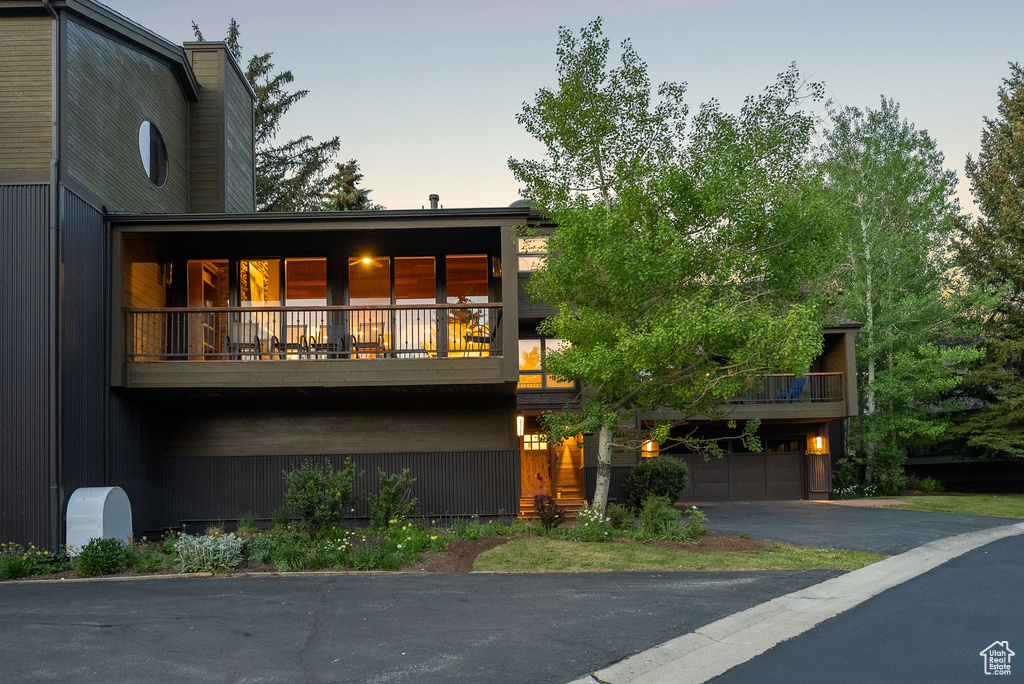 View of front facade featuring asphalt driveway, an attached garage, and a balcony