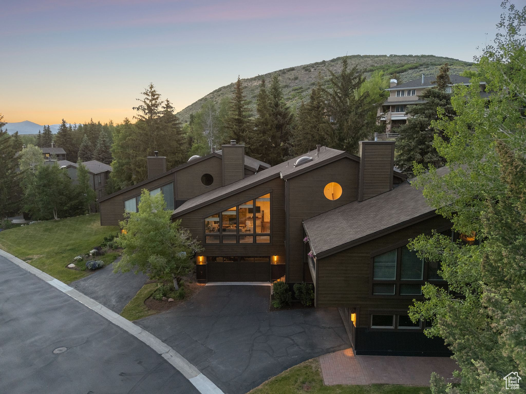 View of front facade featuring a chimney, driveway, a mountain view, and an attached garage