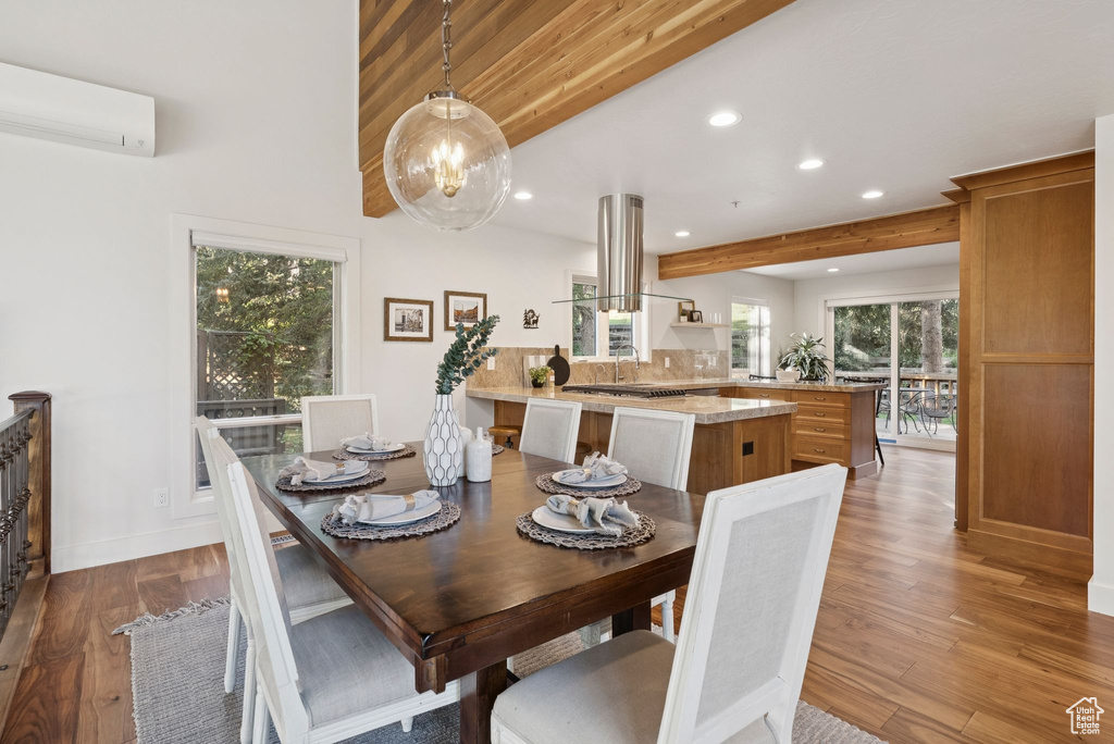 Dining area with a wall mounted air conditioner, recessed lighting, wood finished floors, beam ceiling, and a chandelier