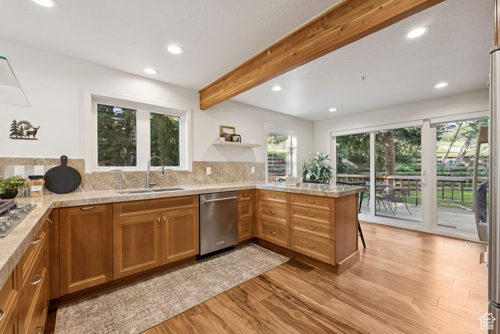 Kitchen featuring appliances with stainless steel finishes, a peninsula, recessed lighting, brown cabinetry, and light wood-type flooring