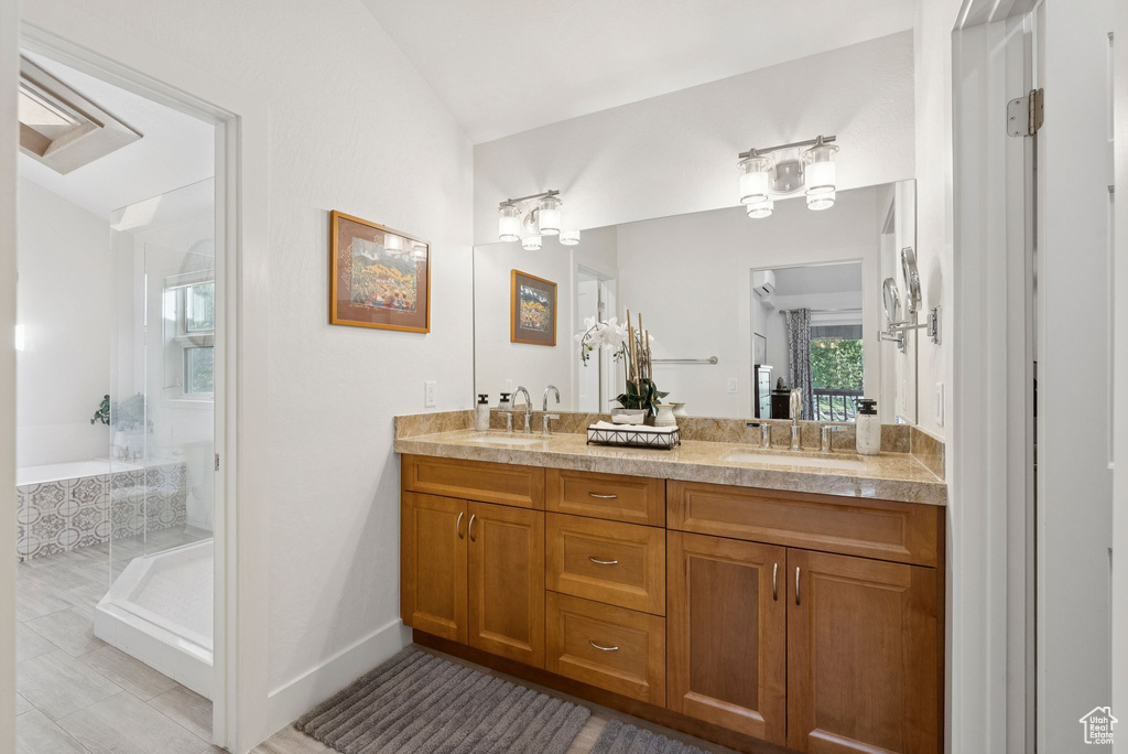 Full bathroom featuring double vanity, a relaxing tiled tub, and vaulted ceiling