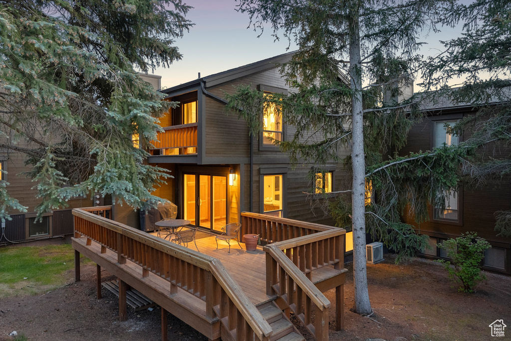Back of property at dusk with a balcony and a wooden deck