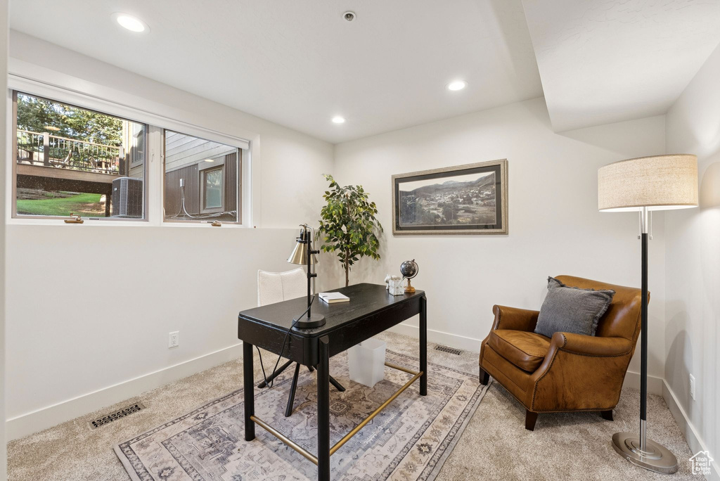 Office space with light colored carpet and recessed lighting