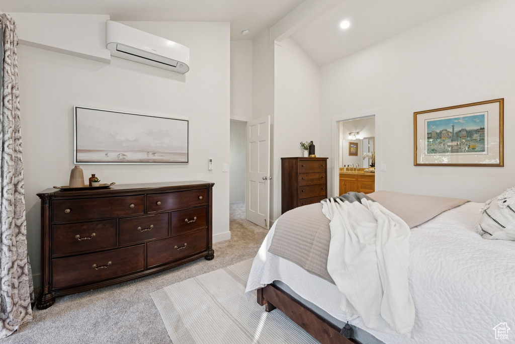 Bedroom with a wall mounted AC, light colored carpet, ensuite bath, and high vaulted ceiling