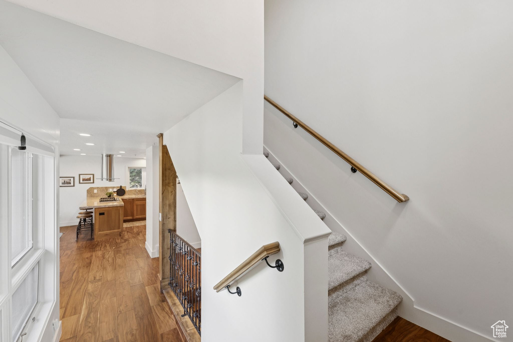 Staircase featuring wood finished floors and recessed lighting